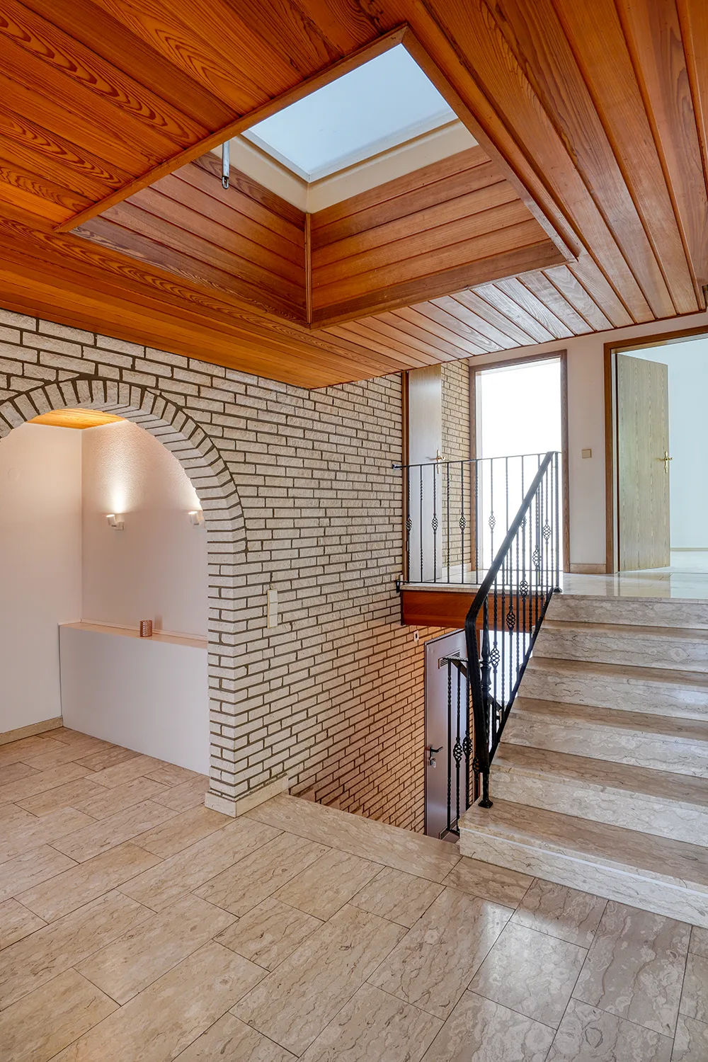 Architektonisches Entree mit Treppe auf unterschiedlichen Ebenen, Sichtmauerwerk und Natursteinboden